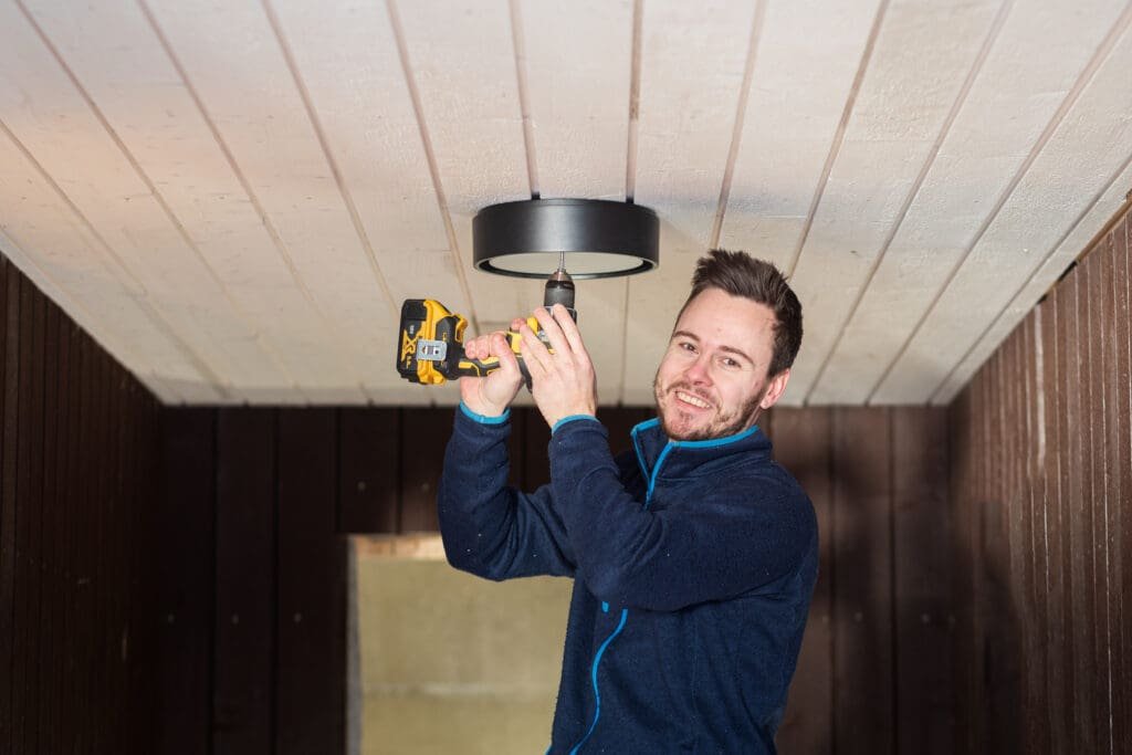mannlig elektriker monterer en lampe i taket